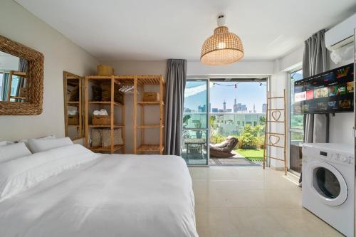 Un dormitorio con una cama blanca y una ventana grande. en ‏ Dizengoff Duplex - Center Tel Aviv, en Tel Aviv