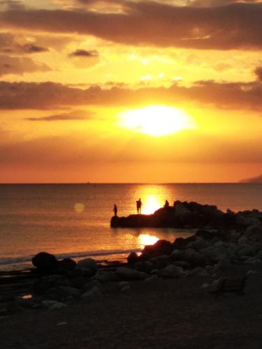 two people standing on a rock in the ocean at sunset at Harmony home in Ierápetra