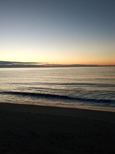 a beach with the sun setting over the ocean at Harmony home in Ierápetra