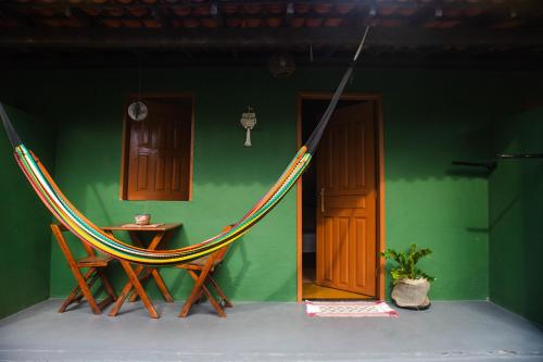 a room with a hammock in a room with a table at Caju com Mel Hospedagem in Moreré