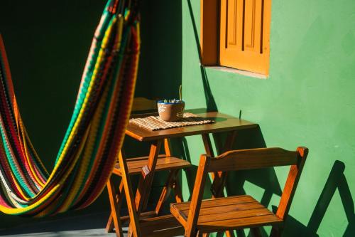 a room with a hammock and a table and a chair at Caju com Mel Hospedagem in Moreré