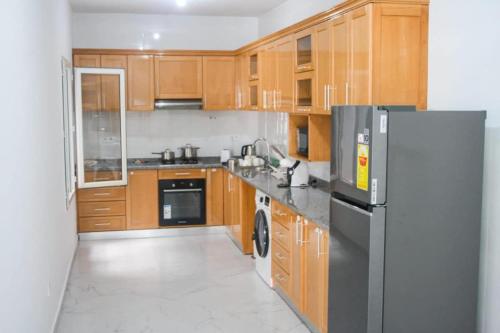 een keuken met houten kasten en een roestvrijstalen koelkast bij Apartment Morabeza in Praia Cidadela in Praia