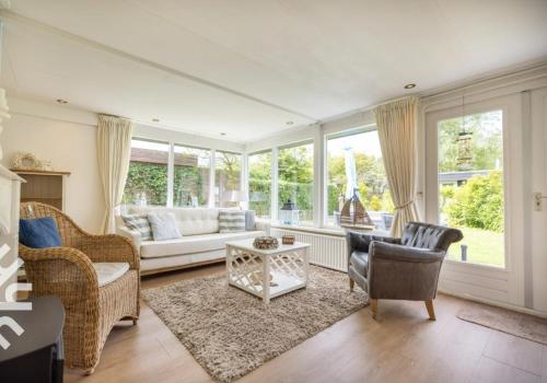 a living room with a couch and chairs and windows at Vakantiebungalow in Riviera Maison stijl nabij zee en strand, bos en duin in Warmenhuizen