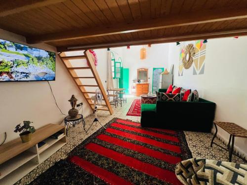 a living room with a television and a red rug at Art riad au bord de la mer 1 in El Jadida
