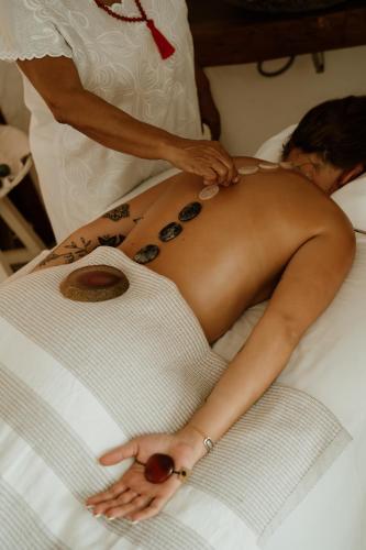 a woman laying on a bed with a man getting a massage at Casa Las Tortugas Petit Beach Hotel & Spa in Holbox Island