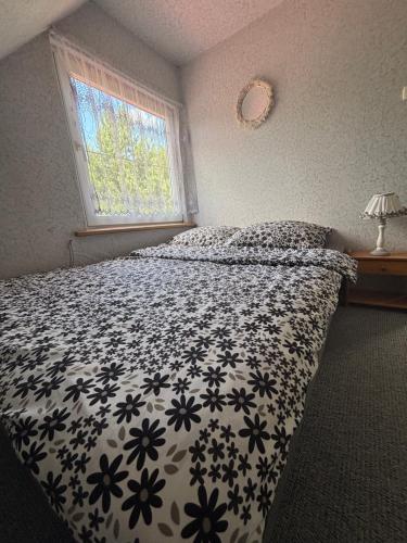a bedroom with a bed with a black and white comforter at U Małgorzaty in Wojtkowa