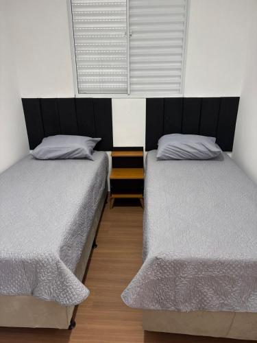 two twin beds in a room with a window at Vista da Mantiqueira - Staffy House Extrema in Extrema