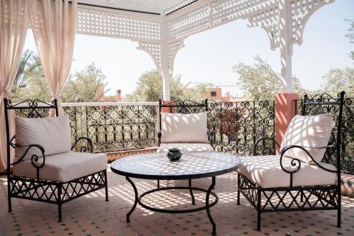 a patio with two chairs and a table on a porch at Villa Marrakchia - Palais d'hôtes & spa in Marrakech