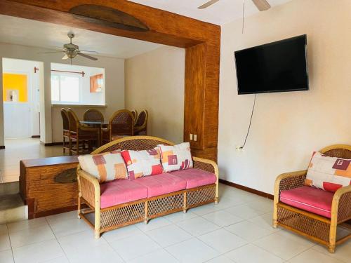 a living room with wicker chairs and a flat screen tv at VILLAS RIBERA DEL PACIFICO in Ixtapa