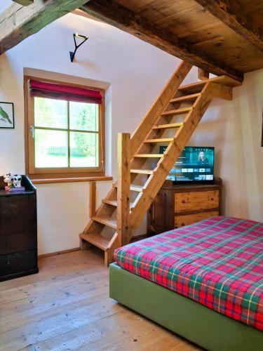 a bedroom with a bed and a wooden staircase at Maso Tre Cucù by Go New Location in Cavalese