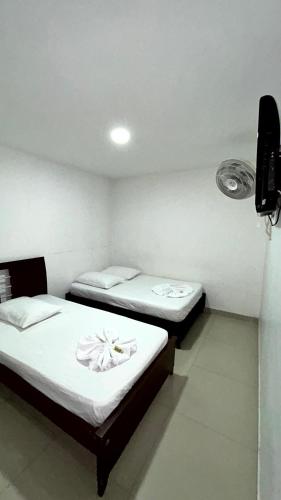 two twin beds in a room with a tv at Hotel Imperio in Ibagué