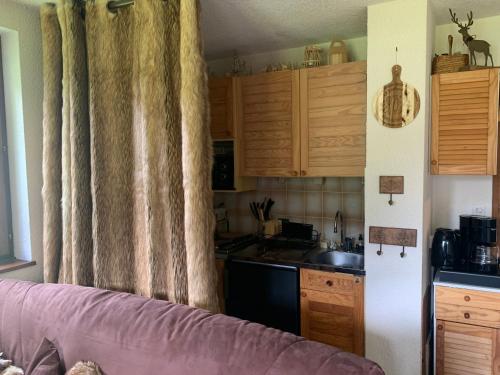 a kitchen with wooden cabinets and a purple couch at Le cocon dans les nuages in La Celle-sous-Gouzon