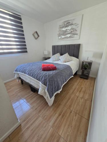 a bedroom with a bed with two red pillows on it at Familiar Departamento 3 dorm 2 baños in Rancagua
