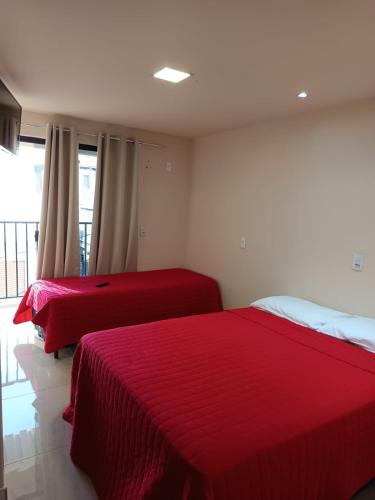 two beds in a bedroom with red sheets at suites montanha das letras in São Thomé das Letras