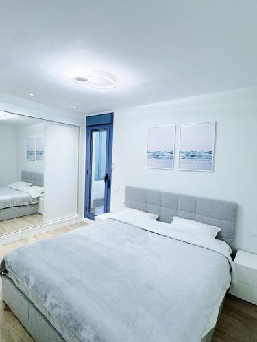 a white bedroom with a large bed and a mirror at Harmony by the Sea in Cambrils