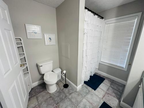 Un baño blanco con inodoro y ventana. en Pets welcome in a spacious 1 bedroom with a fenced in backyard and treadmill, en Cedar Point