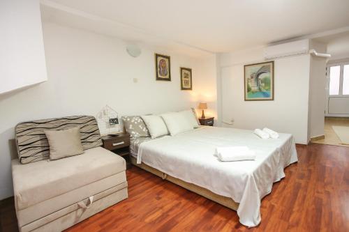 een witte slaapkamer met een bed en een bank bij Apartment Pajevic in Mostar