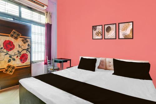 a bedroom with a large bed with a red wall at Hotel O Happy Inn in Gorakhpur