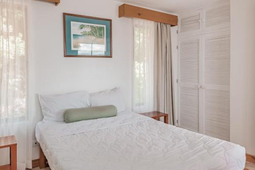 a bedroom with a white bed with a green pillow at Villa Sol 96 in Guanacaste