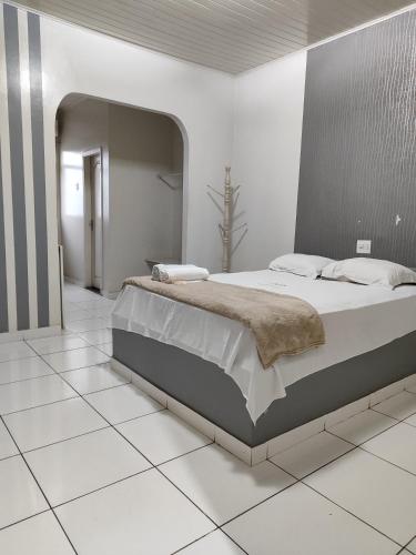 een slaapkamer met een groot bed op een witte tegelvloer bij Hotel Amazonia in Castanhal