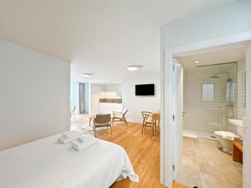 ein Schlafzimmer mit einem weißen Bett und ein Badezimmer in der Unterkunft housingcoruña RUA DO ANXO in A Coruña