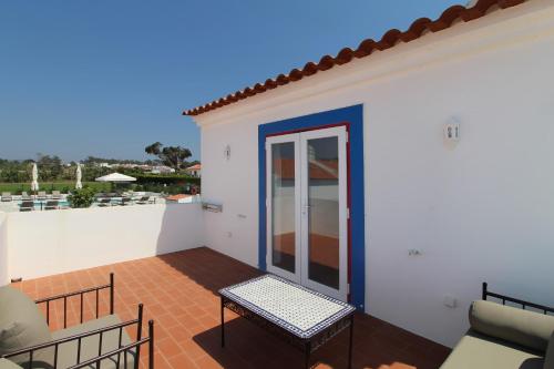 a patio with a glass door on a white building at Quinta do Canal in Vila Nova de Milfontes