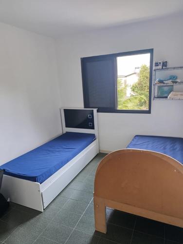 una habitación con dos camas y una ventana en Apartamento Prainha perto de tudo pe na areia - 3 andar escada, en Caraguatatuba