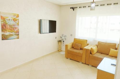 a living room with a couch and a tv at Grand Appartement Idéal - Plein Coeur de Kénitra in Kenitra