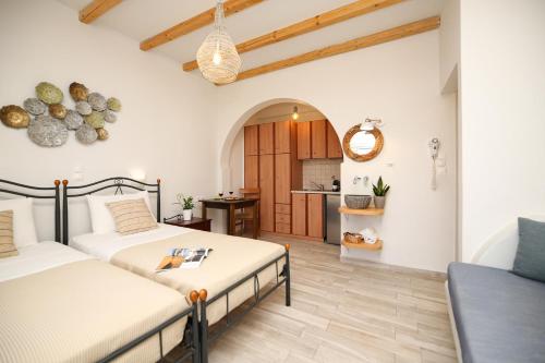 a bedroom with two beds and a kitchen in the background at Ioanna Apartments in Agios Prokopios
