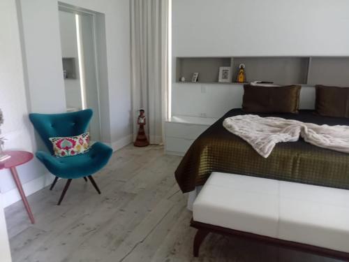 マラゴージにあるCasa jardinsのベッドルーム1室(ベッド1台、青い椅子付)