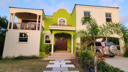 a green and white house with a car parked in front at Serenity in Saint Peter