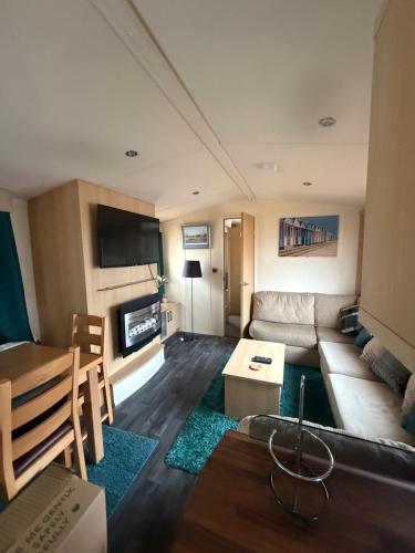 Carlton ColvilleにあるSerenity 2 a gorgeous 3 bedroom 2 bathroom caravanのソファとテーブルのあるリビングルーム
