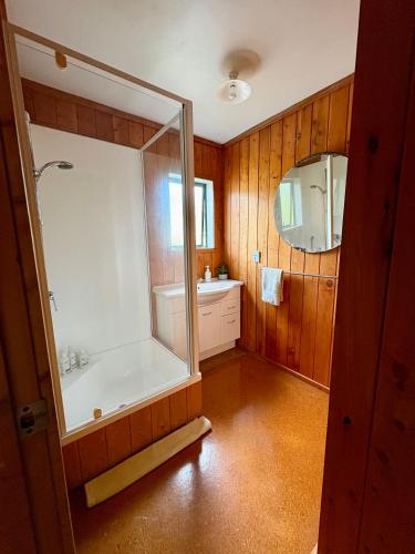 a bathroom with a tub and a sink and a mirror at White Star Station Farm Holiday Park in Coromandel Town
