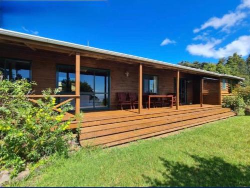 a house with a large wooden deck in the yard at White Star Station Farm Holiday Park in Coromandel Town