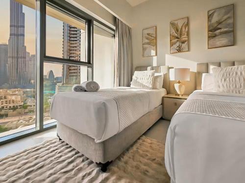 a bedroom with two beds and a large window at Stunning Burj Khalifa View! Steps to Dubai Mall in Dubai