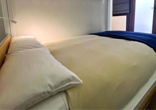 a bed with white sheets and a blue blanket on it at The Hostel Santiago in Santiago