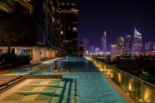 a infinity pool with a city skyline at night at Lè Métropole Saigon in Ho Chi Minh City