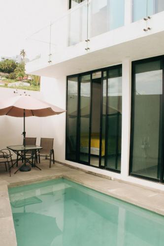 a swimming pool in front of a building with a table and umbrella at Casa Calec 2BR Apartment with Pool & Terrace in Manzanillo
