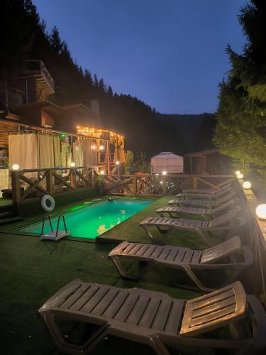 a row of lounge chairs next to a swimming pool at Садиба Бункер ЧАН in Mizhhirʼʼya