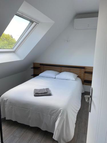 a bedroom with a white bed and a window at Appartement L'Eden de la Guyonnière 2 chambres in Ruaudin