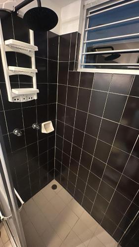 ein Badezimmer mit schwarz gefliesten Wänden und einem Fenster in der Unterkunft Apartamento de Ensueño en Belair Frente al Mar in Caraballeda