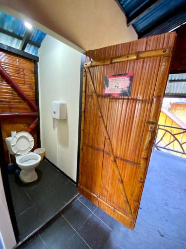 a bathroom with a wooden door and a toilet at Hidden Hostel in Montañita