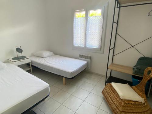 a bedroom with two beds and a chair and a window at Les gîtes de Pailhès in Pailhès