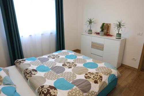 a bedroom with a bed with a comforter on it at Hushu Apartment in Giroc