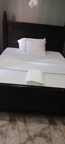 a bed with white sheets and pillows on it at Gorilla African Guest House in Entebbe