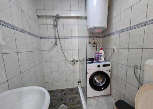 a bathroom with a washing machine and a washer at City Haven Prishtina in Pristina