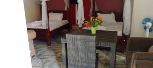 a living room with a table with a vase of flowers on it at Gorilla African Guest House in Entebbe