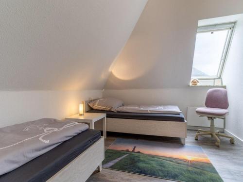 a bedroom with two beds and a chair and a window at Ferienwohnung Küstenluft in Tating in Tating