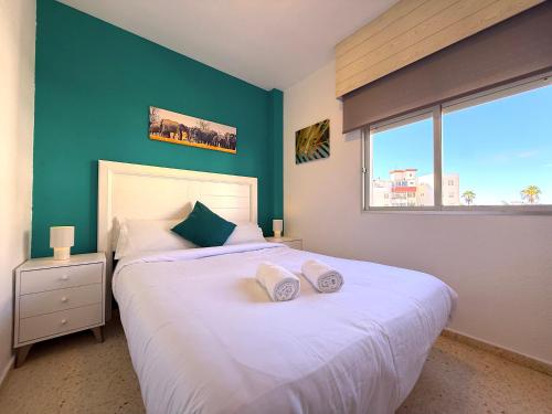 a bedroom with a large white bed with a green wall at Tropicalidays Palmeras del Sur in Adeje
