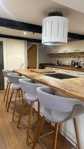 a kitchen with a large wooden counter with bar stools at Entire Cotswolds barn retreat in Carterton